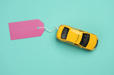 Toy taxi car model with sale tag on blue background. Top view