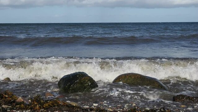 Brandung, Wellen peitschen gegen Steine am Strand der Ostsee