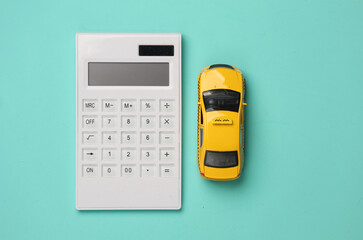 Toy taxi car model with calculator on blue background. Business concept. Top view