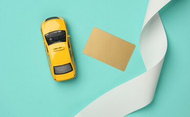 Toy taxi car model with check tape and golden credit card on blue background. Top view