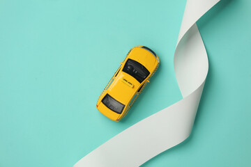 Toy taxi car model with check tape on blue background. Top view