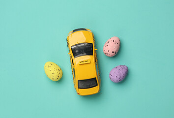 Toy taxi car model with easter eggs on blue background.