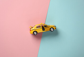 Toy taxi car model on blue pink background. Top view