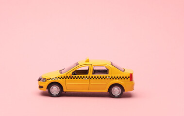 Toy taxi car model on pink background.