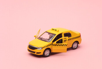 Toy taxi car model on pink background.