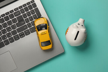 Taxi car with laptop and piggy bank on a blue background. Top view