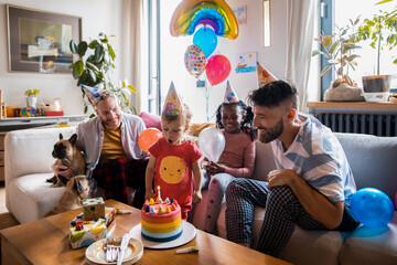 Joyful gay fathers celebrating their child's birthday at home