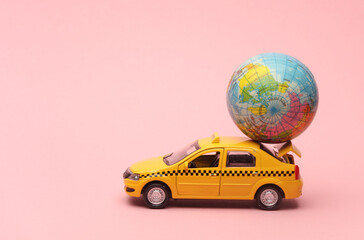 Toy taxi car model with globe on pink background. Travel concept