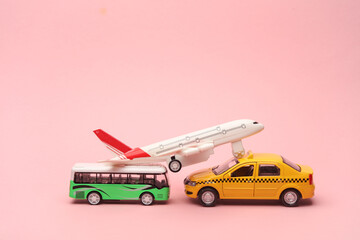 Toy taxi car model with bus and air plane on pink background. Travel concept.