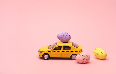 Toy taxi car model with easter eggs on pink background.