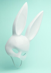 Sexy white rabbit mask with long ears flying in antigravity on blue background with shadow. Levitation object in the air. Creative minimal layout