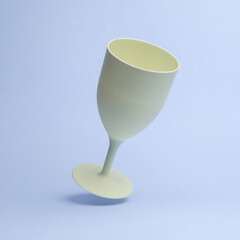 Yellow plastic wine glass flying in antigravity on purple background with shadow. Pastel color trend. Levitation object in the air. Creative minimal layout