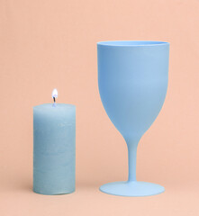 Plastic wine glass with flaming candle on pink background. Pastel color trend