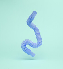 Antistress sensory pop tube toy flying in antigravity on blue background with shadow. Pastel color trend. Levitation object in the air. Creative minimal layout