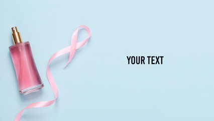 Pink bottle of perfume with a pink ribbon on blue background. Aesthetic beauty still life. Copy space