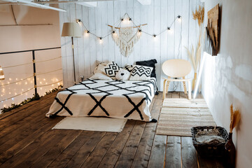 Boho bedroom interior, bed on the second floor of the apartment, white blanket, romantic atmosphere, evening light.