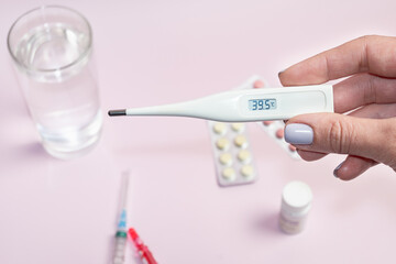 In a female hand is a white electronic thermometer a high temperature. Measured body temperature during illness
