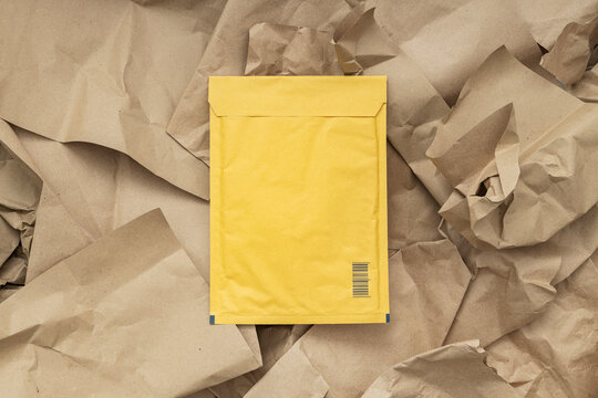 Top view of yellow envelope bag for delivery on the recycled packaging paper. Package for documents delivery