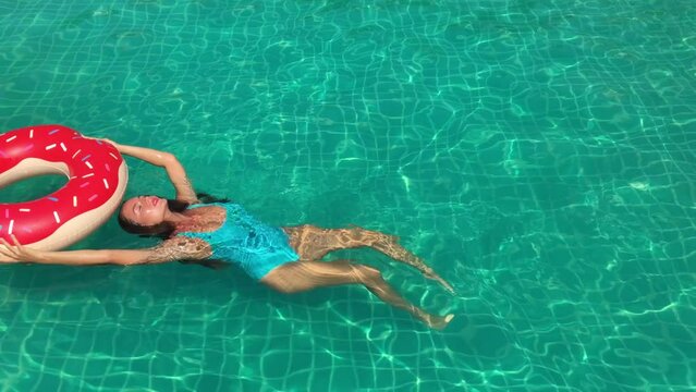 Woman relaxing in swimming pool with inflatable swim doughnut during vacations