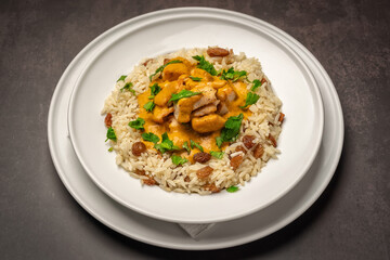 Classic chicken beef stroganoff with rice, raisins and herbs on a marble table.