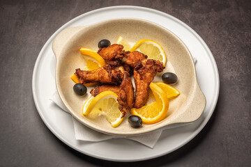 Roasted chicken legs in a vintage plate with citrus lemon and orange and olive berries.