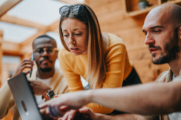 Multiracial business team meets at urban coffee bar. Discussions cover investment, marketing, sales, and strategies for growth and profitability. Collaboration leads to creative brainstorming.