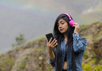 Mujer joven atractiva con auriculares disfrutando de música o un podcast en el parque o bosque,...