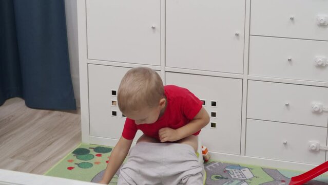 toddler child little boy playing sitting on the potty at home