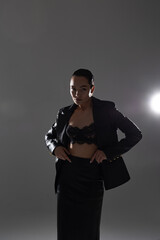 Young pretty woman in black lacy bra and leather suit posing in studio.