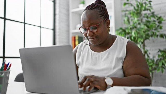 Focused african american woman worker excelling in business. working diligently at her laptop, this boss lady embodies success and professionalism in her office.