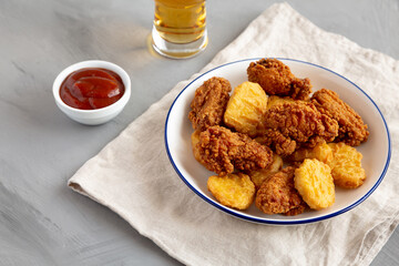 Homemade Chicken Nuggets and Chicken Wings with Ketchup and Beer, side view.