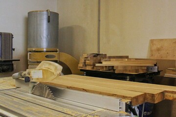 Craft carpentry workshop with variety of wooden pieces and planks, hand tools and wooden work bench in the foreground. Joinery with workbench and lots of wood. Carpenters table with furniture details