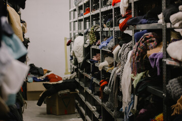 Humanitarian aid station, interior of industrial warehouse with used clothes for poor, refugees,...