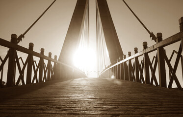 Stunning bright sun rising over the suspension bridge in sepia color