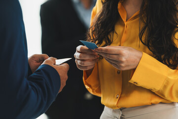 Successful businesswoman holding the name card during talking to manager about their cooperation. Cropped image of exchanging name card between businessman and businesswoman. Side view. Intellectual.