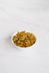 Raisins in a white bowl on a marble table
