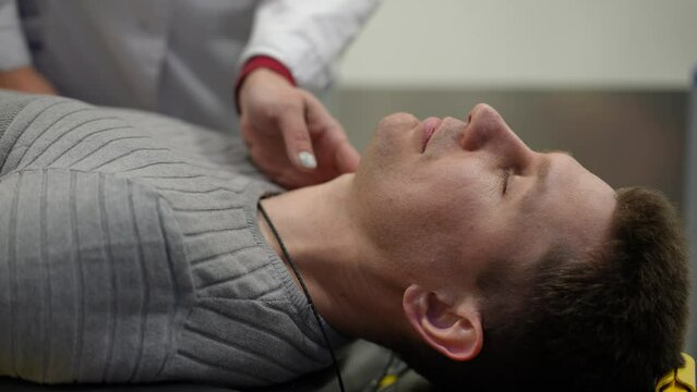 A paramedic checks the pulse of a bedridden man in an ambulance