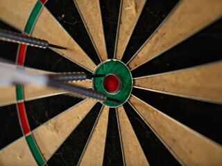 Darts in a dartboard close up. The bullseye is the target but it was missed. The objective is to...