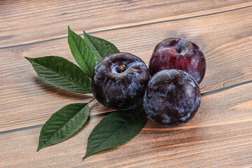 Raw purple plums heap with leaves