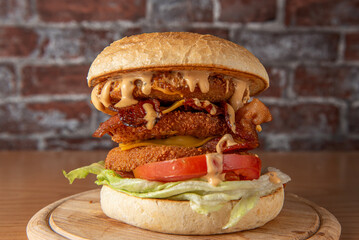 smoked chickenburger centred on wooden plate on dim wall background with bricks