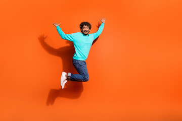 Fototapeta na wymiar Full length photo of overjoyed funny jumping boyfriend celebrate his girlfriend approved him for date isolated on orange color background