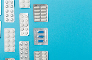 Pills in blister packaging on color background, top view
