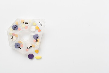 Daily pill box with medications on color background, top view