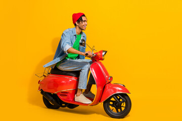 Full length photo of cute young male driving riding motorcycle dressed stylish jeans garment isolated on yellow color background