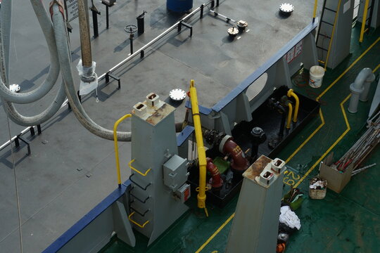Close view on fuel hose of bunker barge  on crane connected to container vessel in bunker station with valves and manifolds during transferring of diesel or bunkering. 