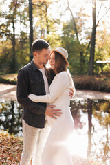 Young stylish couple lovers are hugging in the autumn park. Lovely romantic moment between man and woman in love. Happy family. Love, youth, happiness concept.