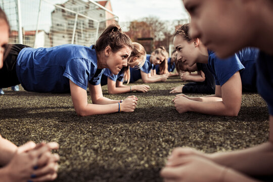 Female soccer team performing plank exercises on the training field