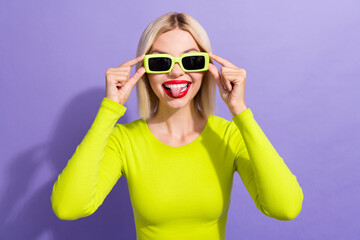 Portrait of good mood woman with bob hairdo dressed yellow top touch sunglass showing tongue...