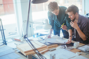 Two young male designers looking at paperwork in a office