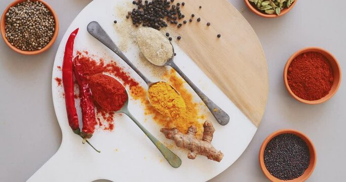 Spices, colorful and herbs on table in kitchen for cooking, food or seasoning collection with color. Top View, curry and tumeric or salt with seeds, cumin and masala or powder on arrangement board